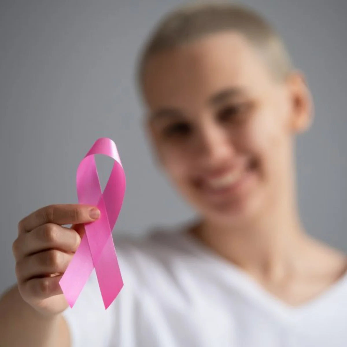 Femme avec les cheveux rasés montrant un ruban rose son support pour le cancer du sein