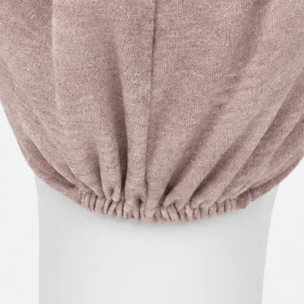 Vue rapproché de l'élastique d'un bonnet confort en tricot rose sur fond blanc