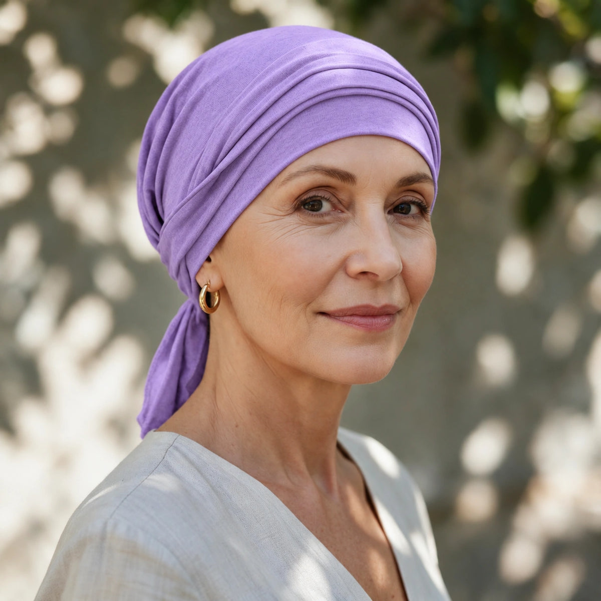 Femme confronté à la perte de ses cheveux du au cancer ou à la chimiothérapie portant un foulard à corde Sibelle en bambou lilas noué croisé.