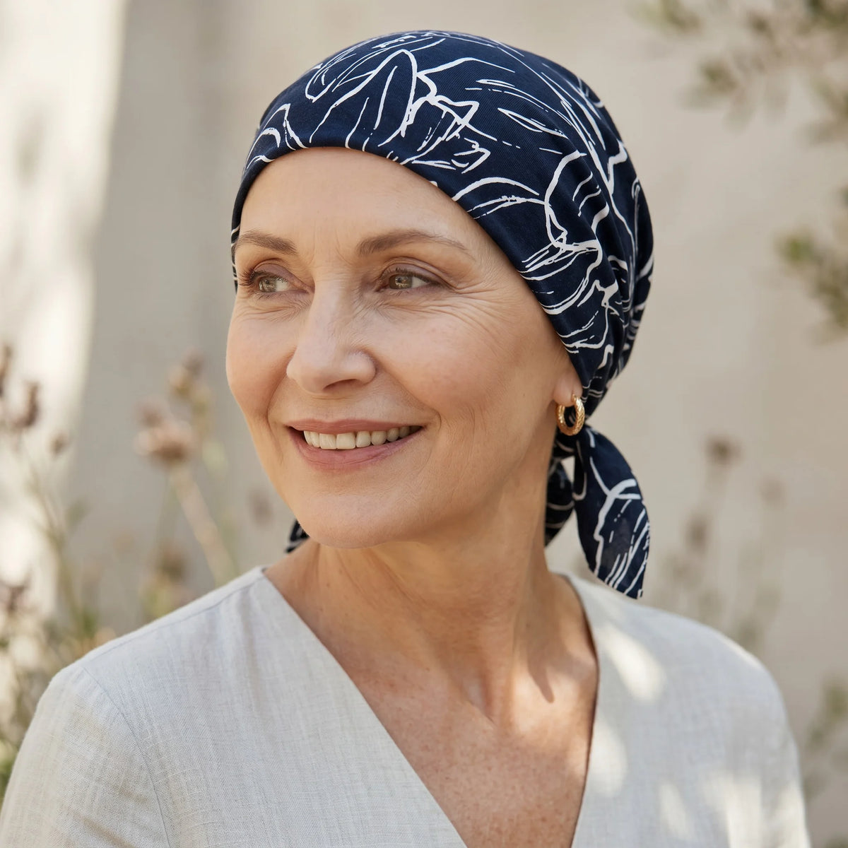 Femme vivant avec une perte de cheveux du au cancer ou à la chimiothérapie avec un foulard rétro darcy bleu Sibelle à l'extérieur