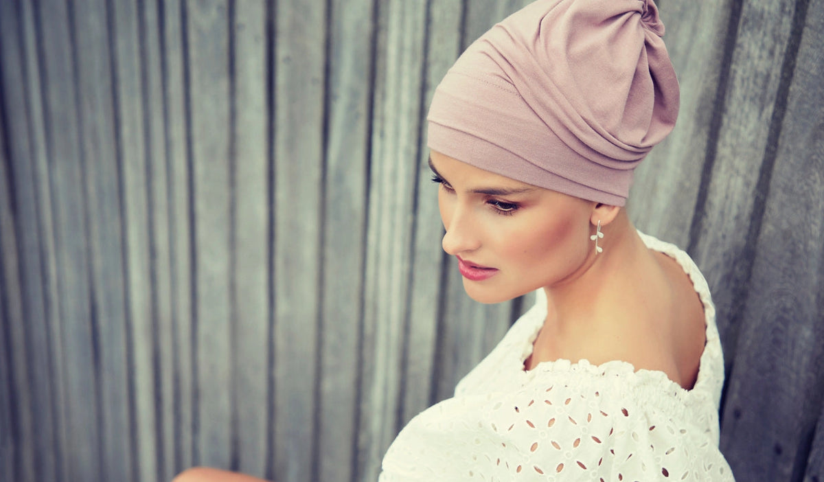 Femme vivant avec une perte de cheveux du au cancer ou à la chimiothérapie portant un foulard tube rose Sibelle