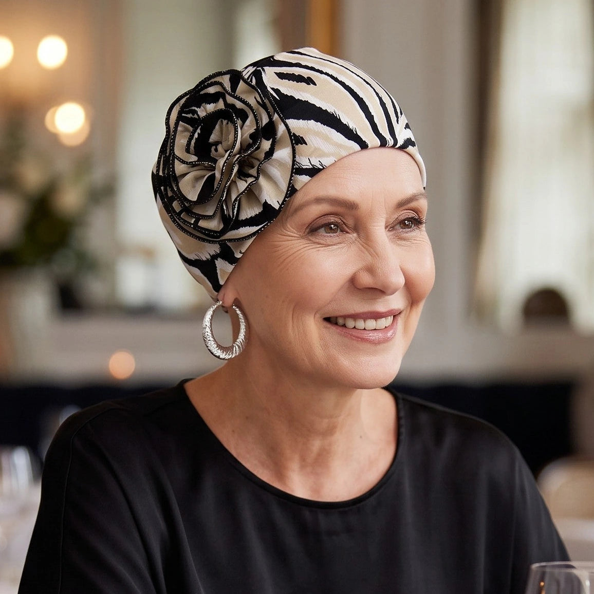 Femme vivant avec une perte de cheveux du au cancer ou à la chimiothérapie avec un bonnet flora palmier noir Sibelle au restaurant